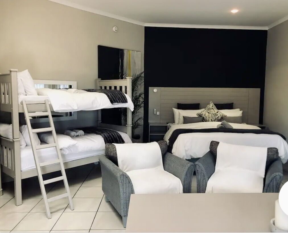A hotel room with a bunk bed, a desk, and a chair.