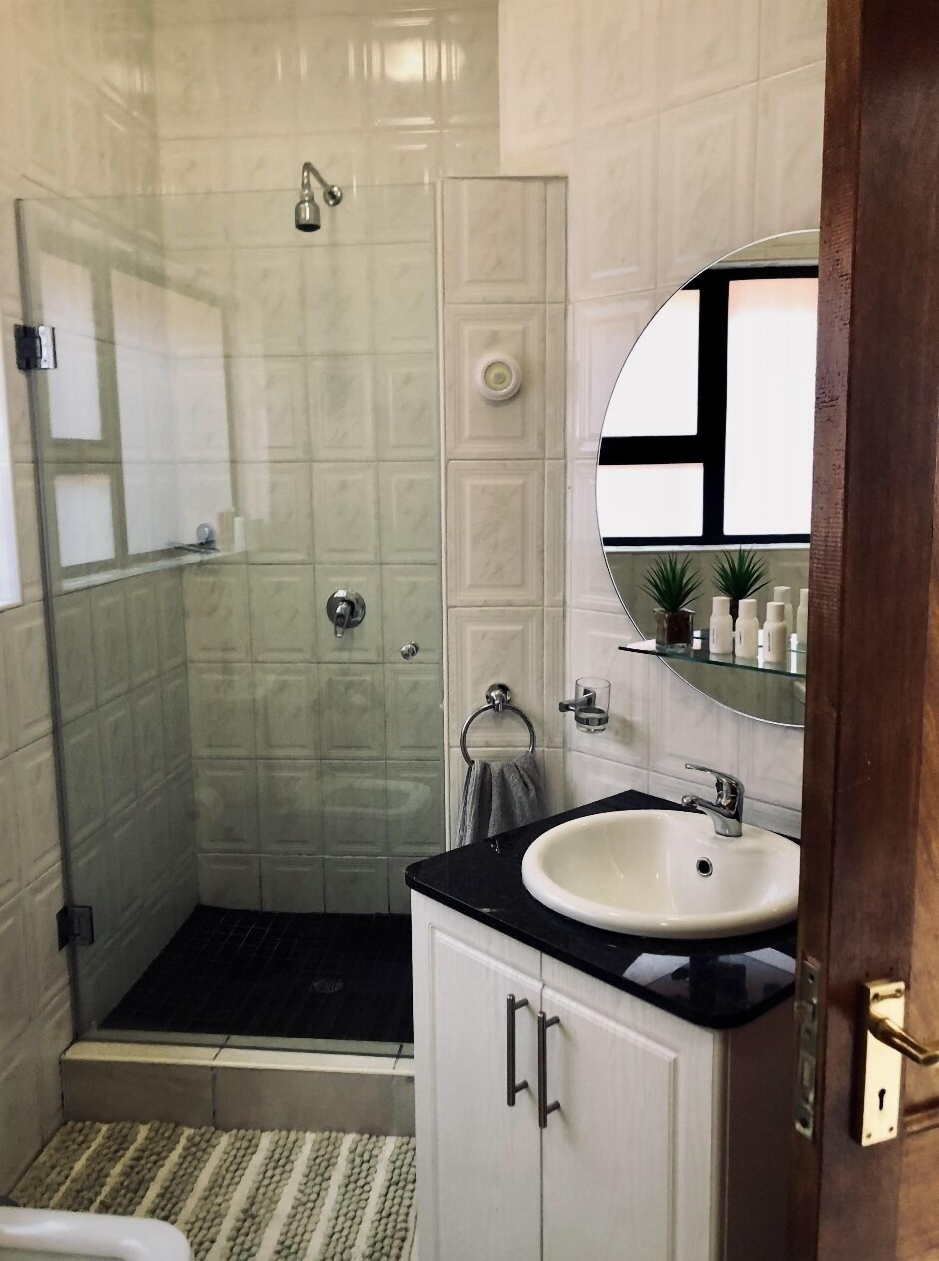 A bathroom with a shower, a sink, and a mirror.