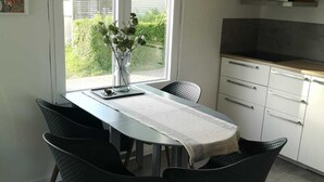 Un comedor con una mesa, sillas y vistas a zonas verdes.
