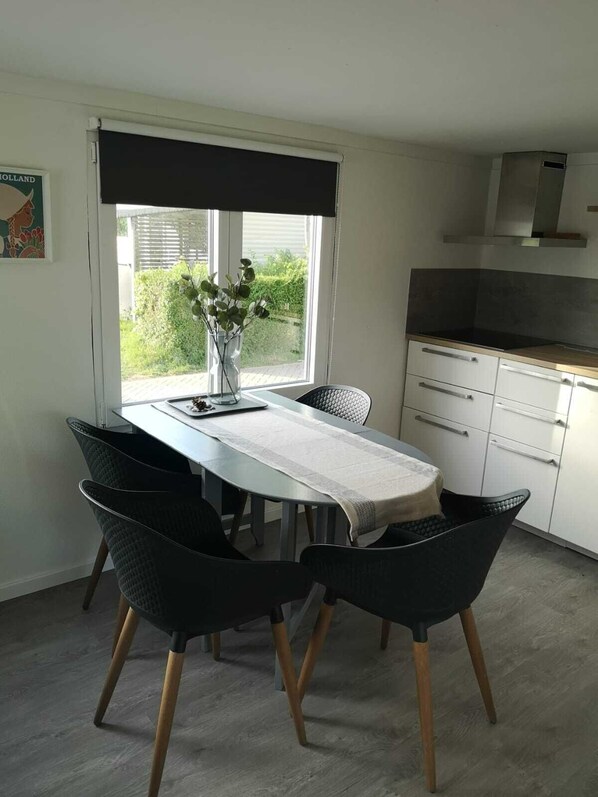 A dining area with a table, chairs, and a view of greenery outside.