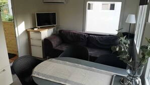 Un espacio habitable compacto con kitchenette, un sofá, una mesa de comedor y un televisor.