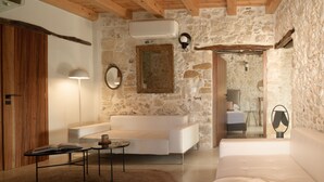 Un soggiorno moderno con una parete in pietra, un divano bianco, un tavolino da caffè e un soffitto in legno.