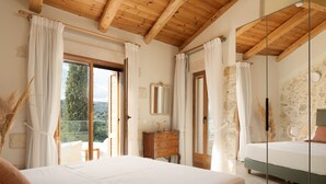 Una camera da letto con soffitto in legno, un grande specchio, un letto, una cassettiera e vista sull'esterno.