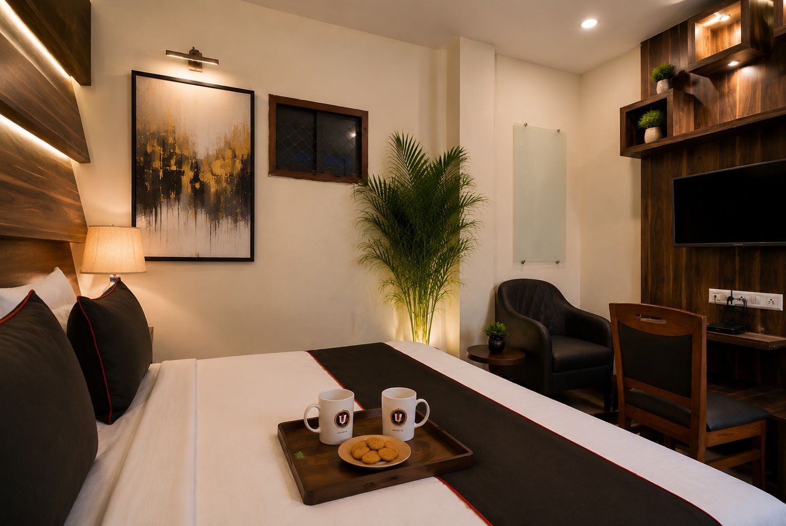 Una habitación de hotel con una cama, un escritorio, una silla, un televisor, una planta y obras de arte en la pared.