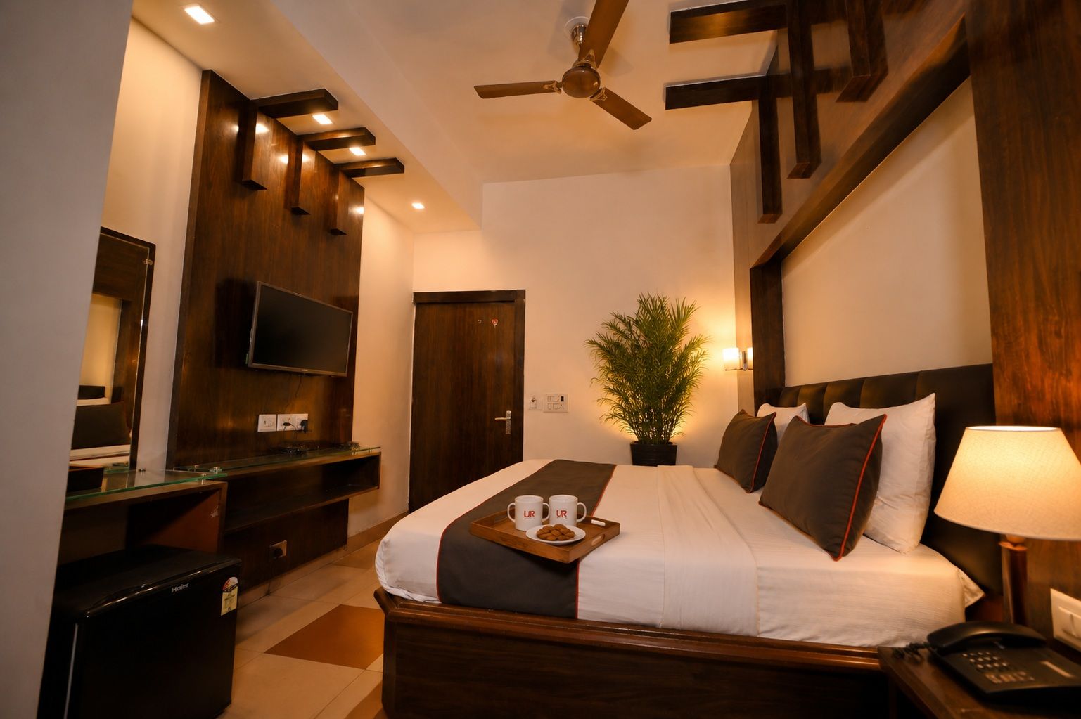 Ein Hotelzimmer mit Bett, Nachttisch, Lampe und Fernseher.