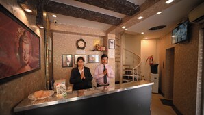 A reception desk with a Buddha statue, framed pictures, and a QR code. - Hotel Ur (Prayagraj)