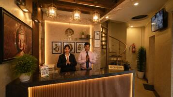 Una recepción de hotel con una estatua de Buda, obras de arte enmarcadas y un diseño moderno.