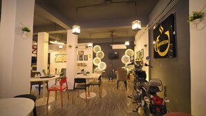 A restaurant interior with round tables, chairs, hanging lights, and a motorcycle.