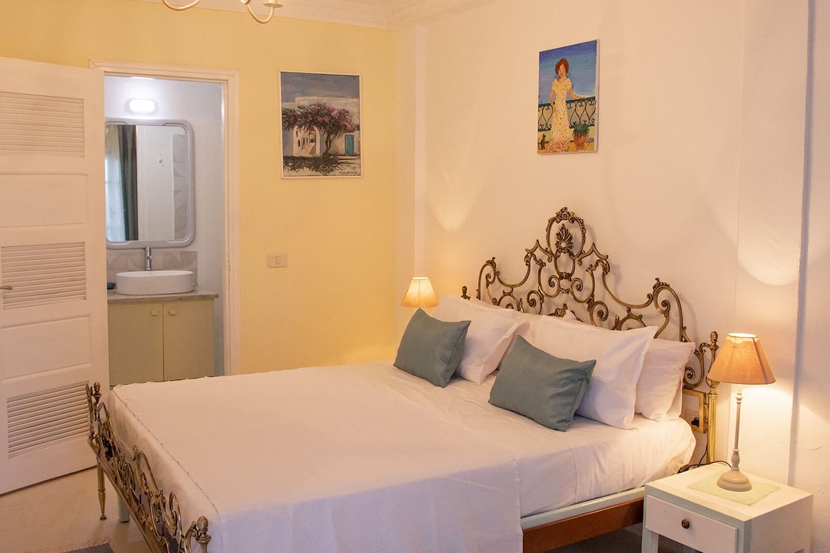 A neatly made bed with a headboard, bedside lamps, and a small bedside table.