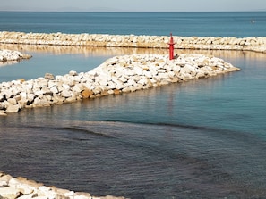 A rocky breakwater with a red lighthouse, calm sea, and clear sky. - dar Yessine  (Hergla)
