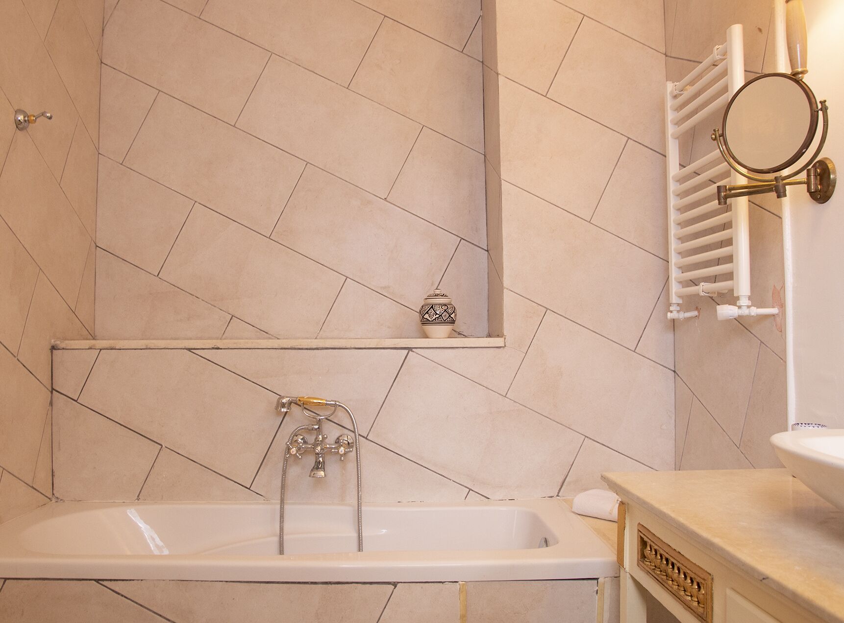 A bathroom with a bathtub, a mirror, a towel rack, and a shelf with a decorative item.