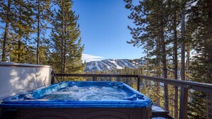 A hot tub on a balcony with a view of a snowy mountain.