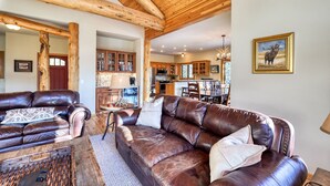 A spacious living room with a leather sofa, a coffee table, and a dining area with a wooden table and chairs.