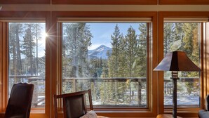 A cozy room with large windows offering a view of a snowy mountain and forest.