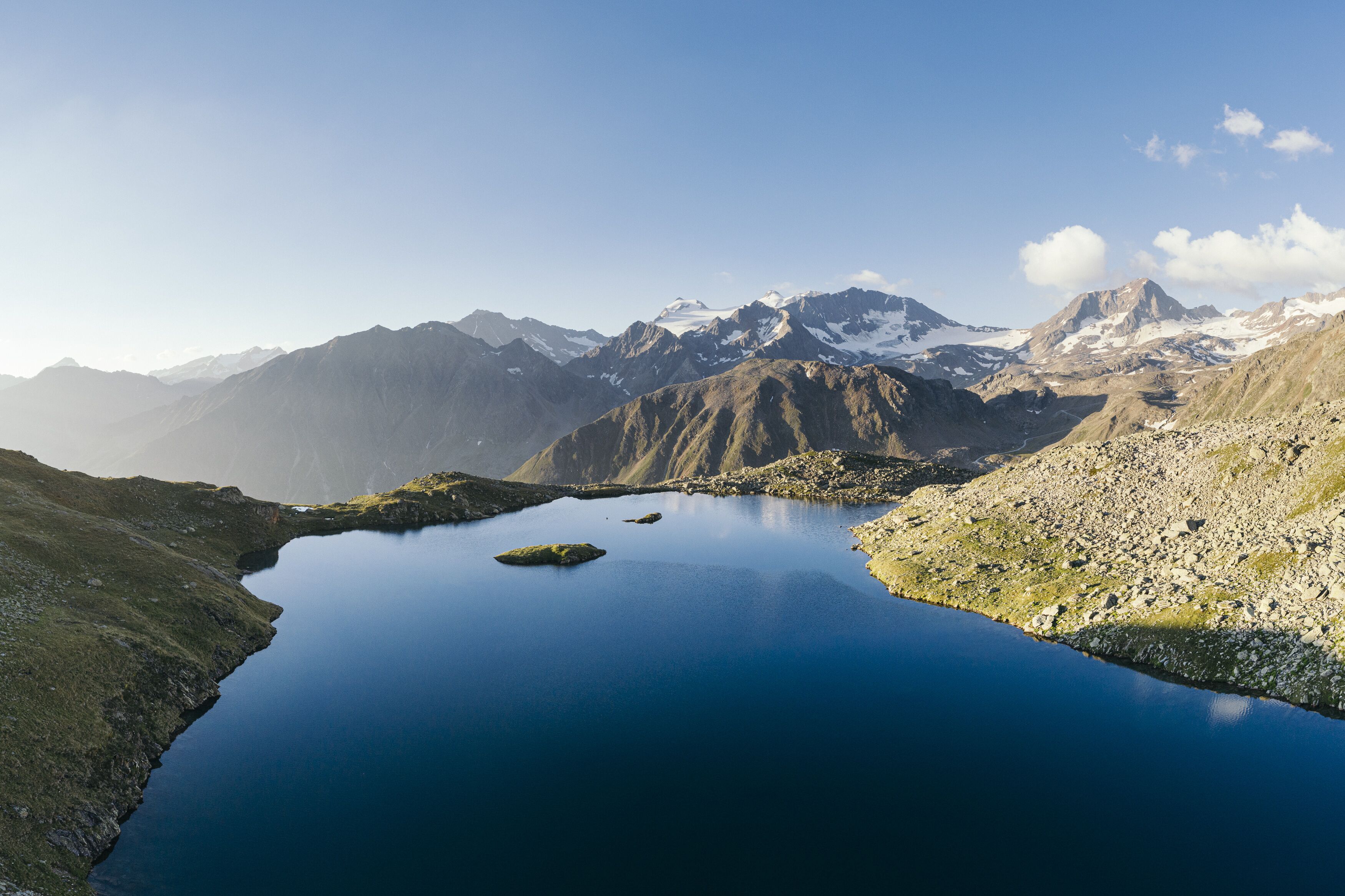 A serene mountain lake with clear water, surrounded by rugged mountains and sparse vegetation.