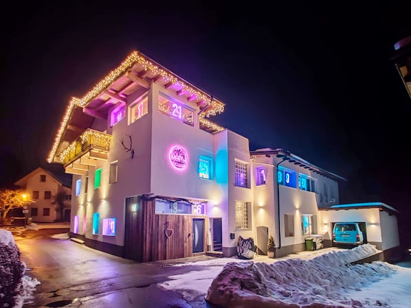 A modern two-story building with illuminated windows and a neon sign. - Doug's Mountain Getaway (Fulpmes)