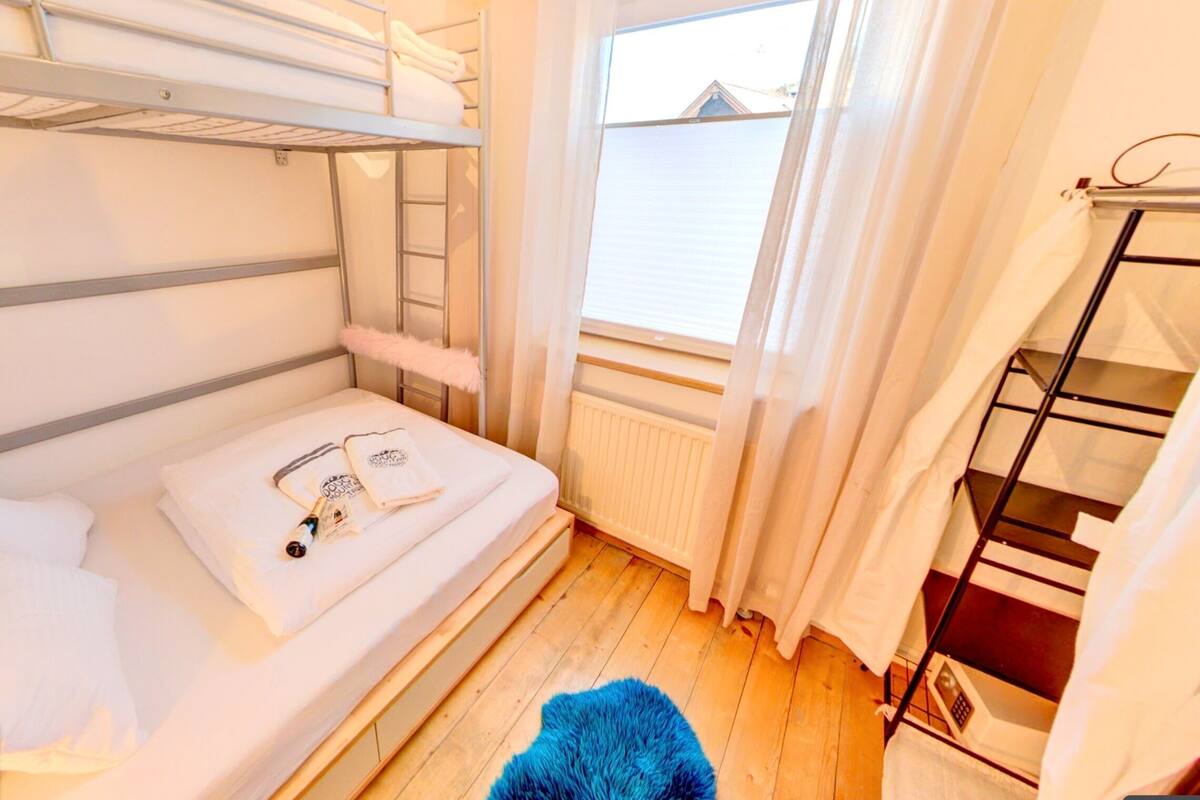 A bunk bed room with a window, a radiator, and a blue rug.