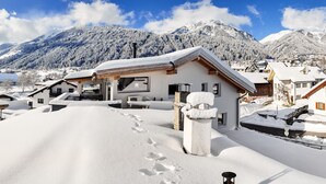 A snow-covered village with traditional Alpine architecture, including a chalet with a sloped roof and a circular building with a conical roof. - Doug's Mountain Getaway (Fulpmes)