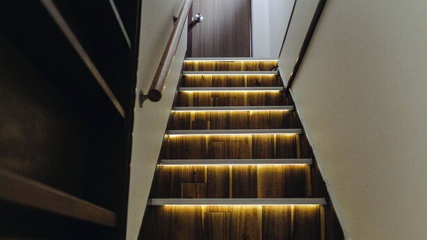 Una escalera de madera con barandilla que lleva a una puerta en la parte superior.