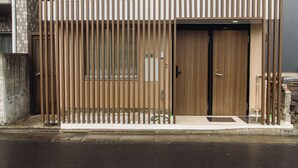 Un edificio moderno con fachada de madera, entrada portonada y una puerta visible.