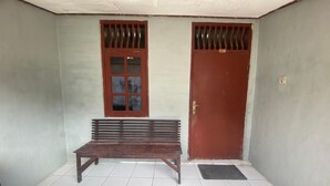 Una habitación con un banco, una puerta y una ventana con diseño de cuadrícula.