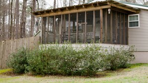 A house with a covered porch, wooden fence, and dense shrubbery.