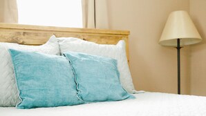 A bed with white and blue pillows, a wooden headboard, and a floor lamp.