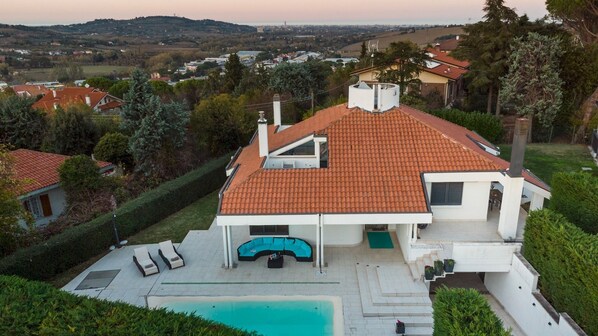 A modern house with a swimming pool, a covered patio, and a view of the surrounding landscape. - Villa Vae Victis 6, Emma Villas (Coriano)