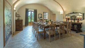 A dining area with a large table set for six, surrounded by wooden chairs. There is a wooden cabinet and a mirror on the wall.