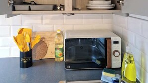 A kitchen with wooden cabinets, a microwave, and various kitchen utensils and appliances. - £ - City Centre - Duke Street Studio ~ 5* Location (Liverpool)