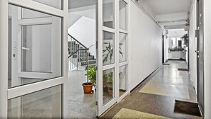 Un corridoio moderno di un hotel con porte in vetro, una scala e piante in vaso.