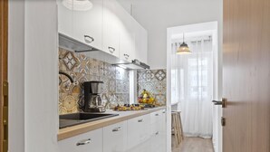 Una cucina moderna con mobili bianchi, un backsplash fantasia e una macchina da caffè.