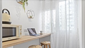 Una cucina con un forno a microonde, un laptop sul bancone e due sgabelli di legno.