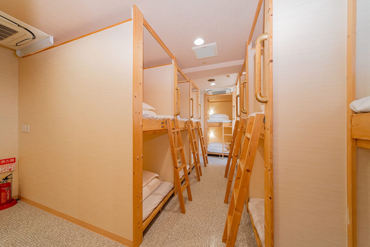 A corridor with bunk beds, a fire extinguisher, and an air conditioning unit.