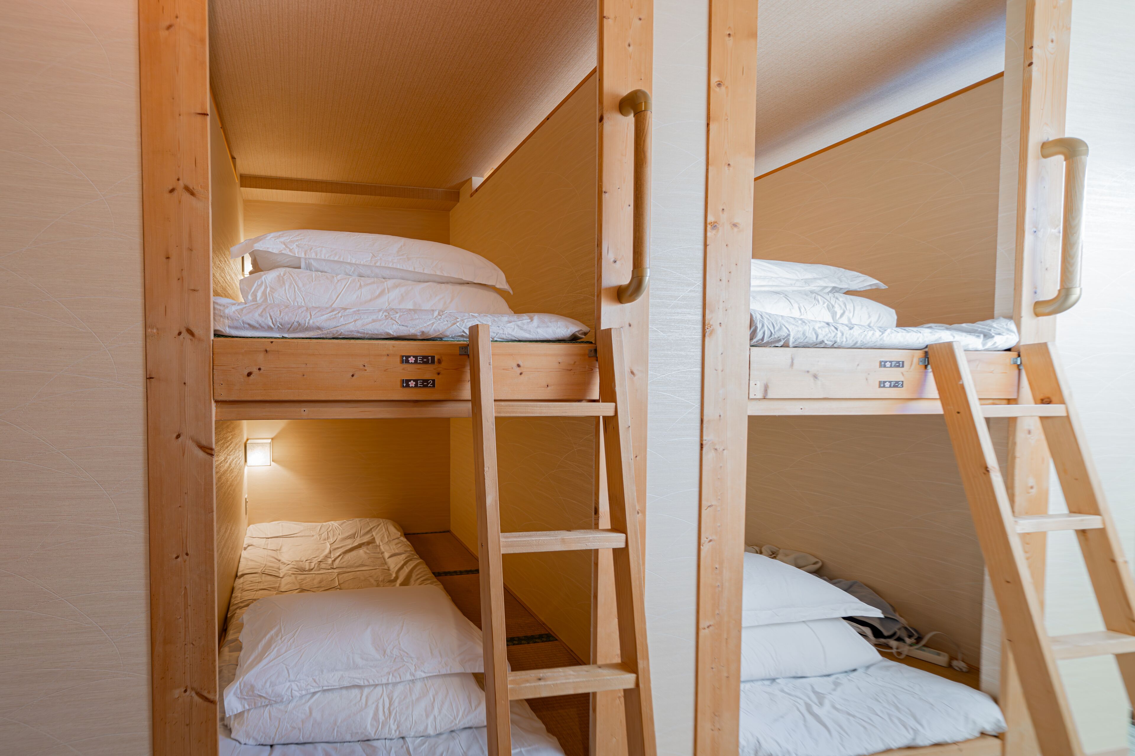Ein Schlafzimmer mit Etagenbetten, Holzleitern und einem kleinen Regal.