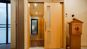 A hotel lobby with a wooden door, a public bath sign, and a reception area.
