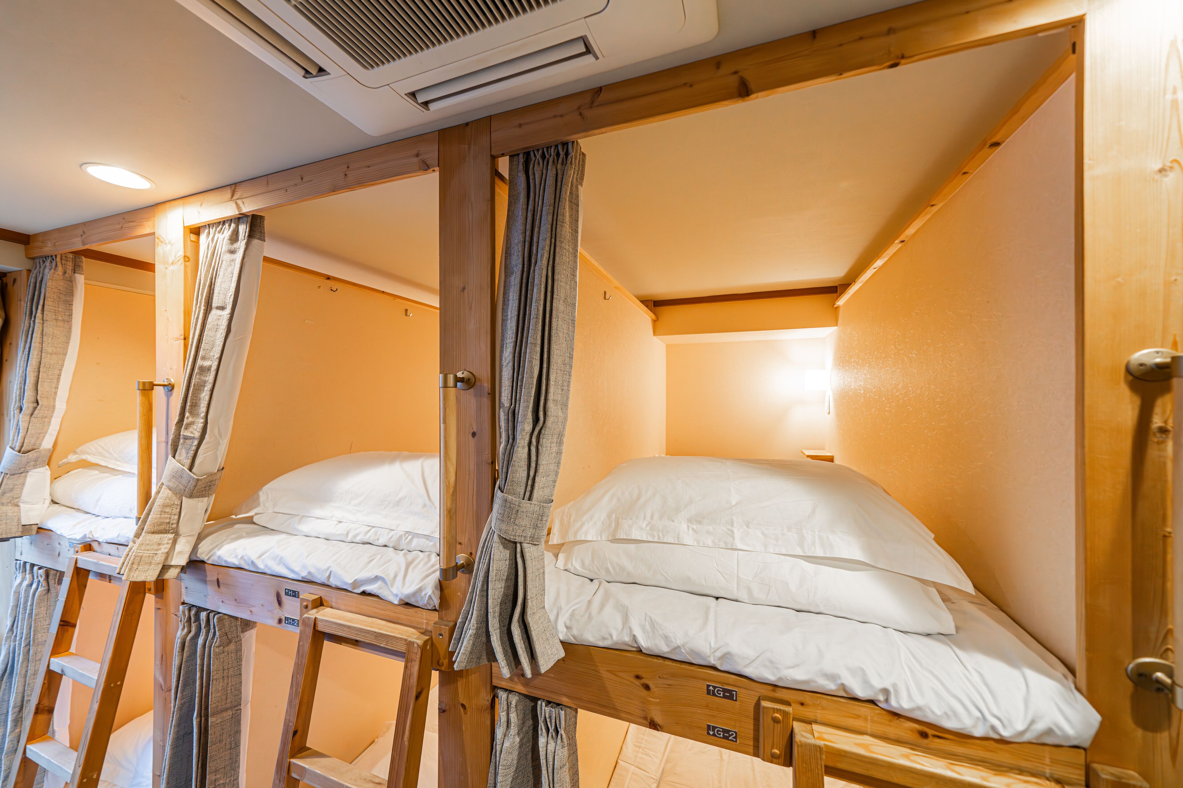 A room with bunk beds, wooden beams, and a ceiling vent.