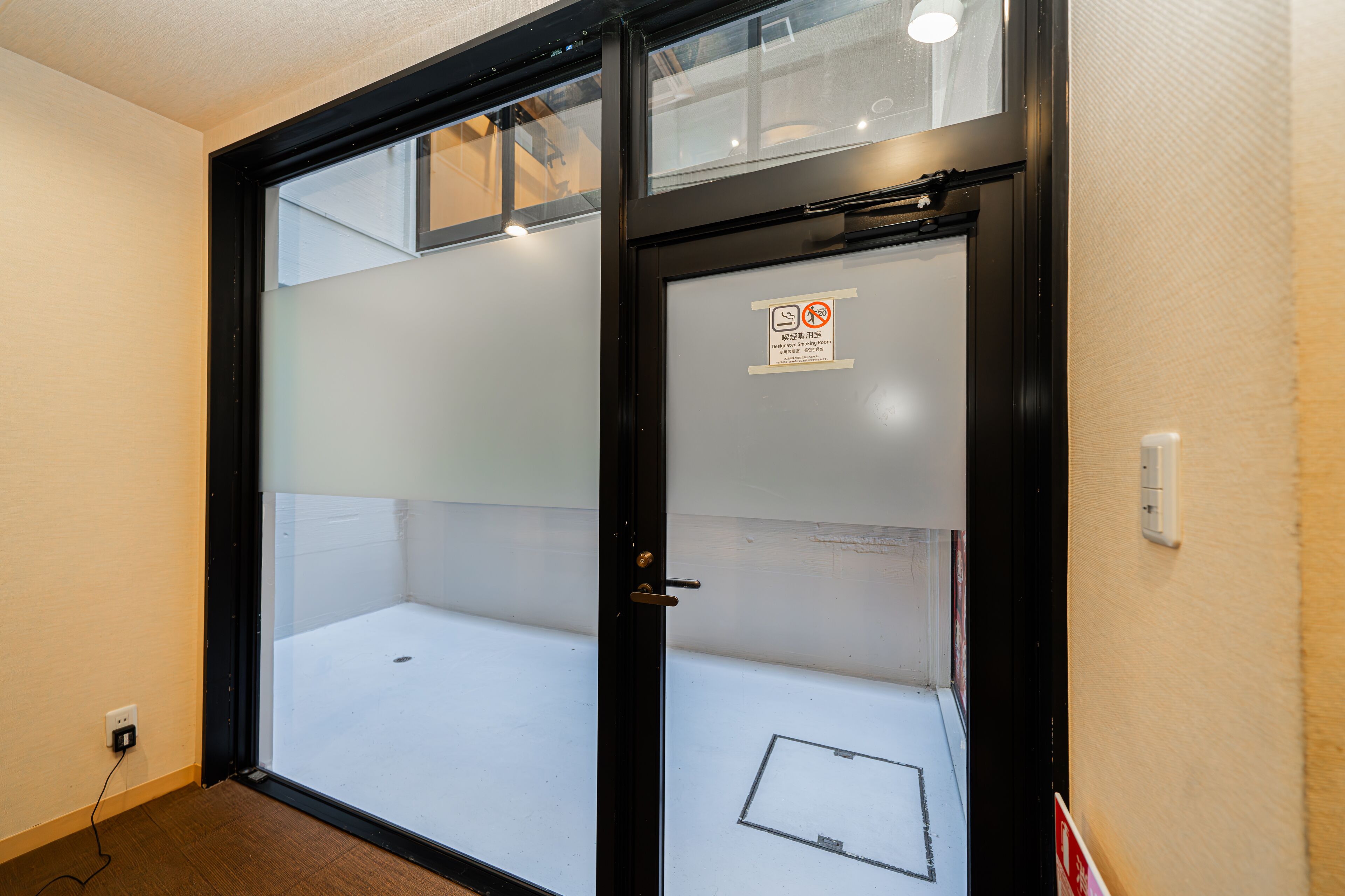 A closed sliding glass door with a 'No Entry' sign, a power outlet on the wall, and a small window above the door.