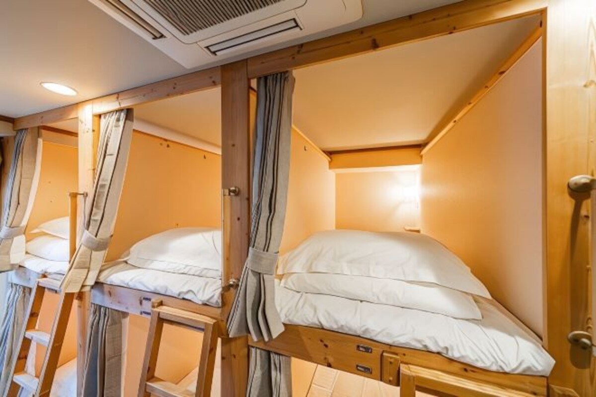 Une chambre avec des lits superposés, des cadres en bois et un ventilateur de plafond.