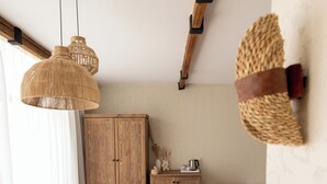 A room with a wooden cabinet, a round wooden stool, a cushioned bench, and a hanging woven light fixture. - Sphinx House (Giza)