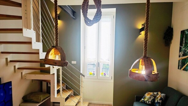 A modern interior with a staircase, a hanging light fixture, and a sofa.