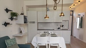 A modern kitchen with white cabinets, a dining table set for four, and pendant lights.