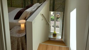 Een modern interieur met een dakraam, een trap en een bed met nachtkastje.