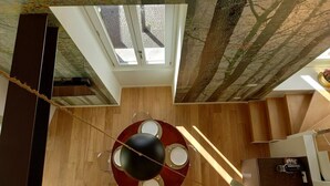 Een moderne keuken met een centraal eiland, een eethoek met een ronde tafel, en uitzicht op het buitengebied door een dakraam.
