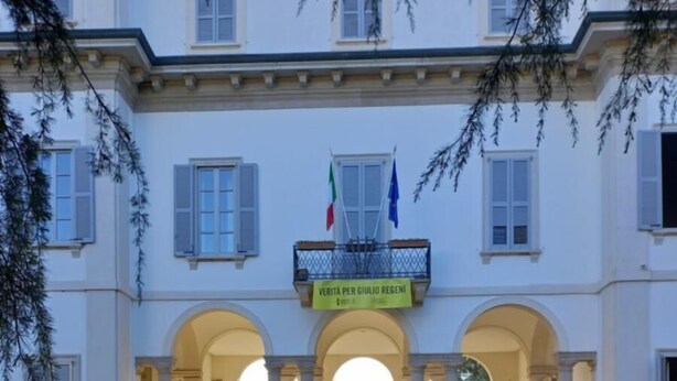 A building with a central courtyard, arched entrances, and a flag on the roof. - Ca'Foulard3: a dip in the blue (Cernusco sul Naviglio)