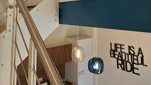 A modern interior with a staircase, a wall with a motivational quote, and pendant lights. - Ca'Foulard3: a dip in the blue (Cernusco sul Naviglio)