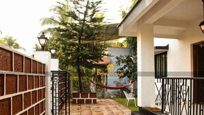 A house with a tiled patio, a hammock, and a gate. - Privy Stays Reed Field Cottage (Alibag)