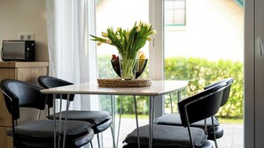 A modern dining area with a table, chairs, a lamp, and a vase of flowers. - Ferienwohnung Uferpromenade mit Terrasse (Röbel/Müritz)