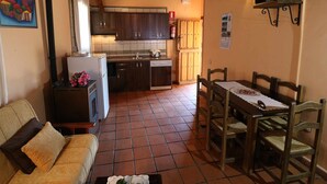 Un espai vital compacte amb buguer, una zona de menjador amb taula i cadires, un sofà i un televisor penjat a la paret.