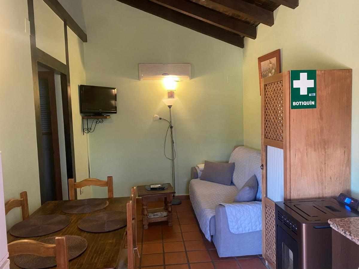 Ein gemütliches Wohnzimmer mit einer Couch, einem Esstisch mit Stühlen, einem Fernseher, einer Lampe und einer Holzeinrichtung mit einem Schild.